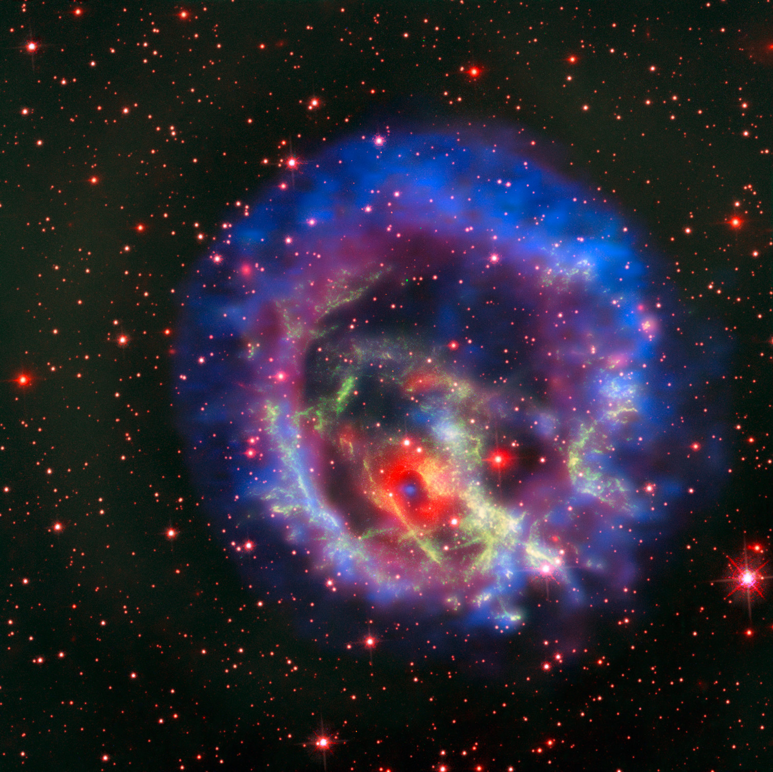 A neutron star appears as a blue spot surrounded by shells of material which appear as red and green rings