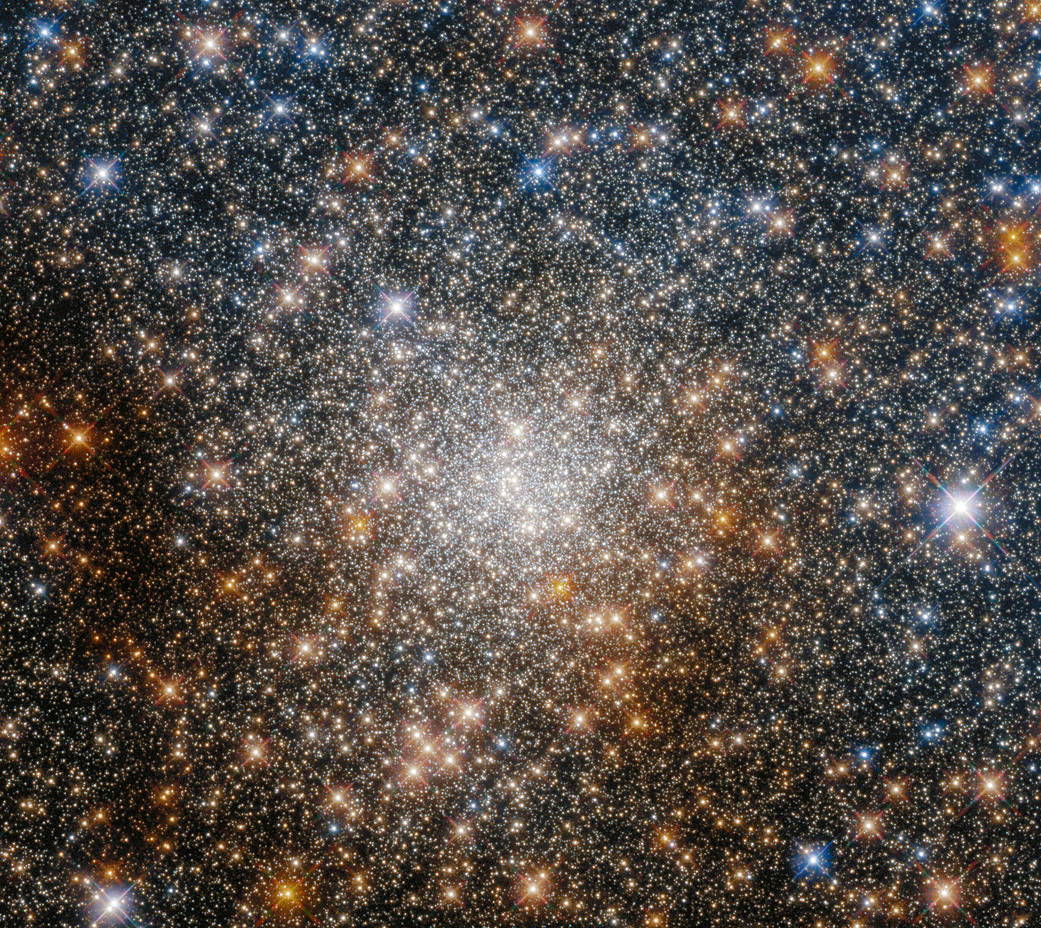 A cluster of stars of may different colours. The stars are heavily concentrated in the centre of the image