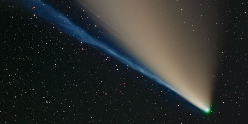 A comet with two tails, one is yellowish and gradually spreading away from the nucleus, the other is blue and compact