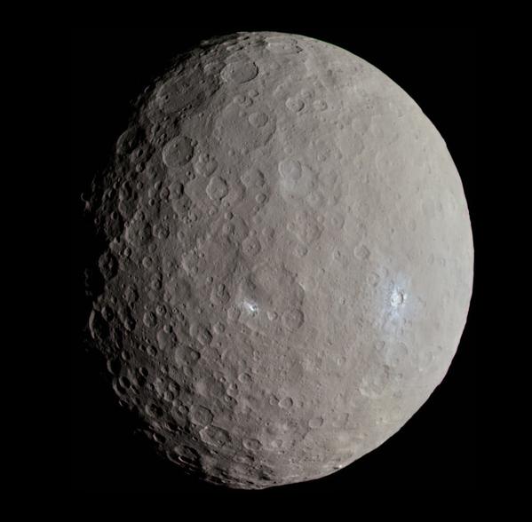 The asteroid Ceres, roughly spherical with a grey surface, many craters, some of which reveal white subsurface water ice.