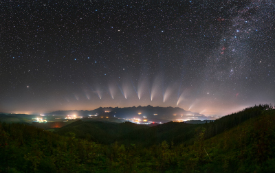 彗星的多幅圖像在城市的夜空中形成一道弧線，其彗尾遠離地平線