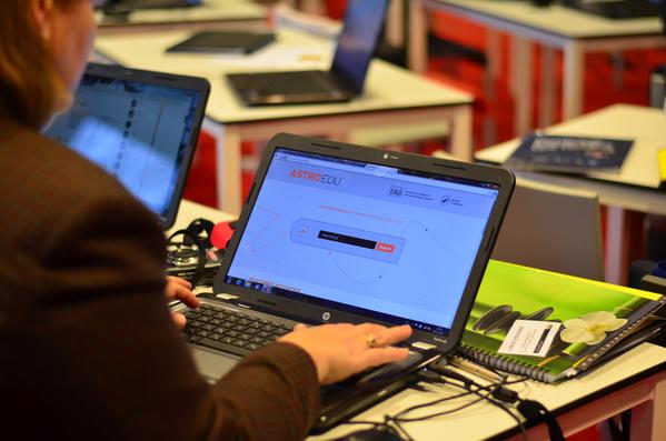 A person using a laptop. The laptop screen displays the astroEDU homepage