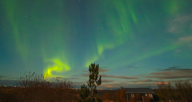 Curved green bands of light radiate out from the horizon, diffusing to wider bands at the top of the image.