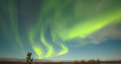 Curved green bands of light radiate out from the horizon, diffusing to wider bands at the top of the image.