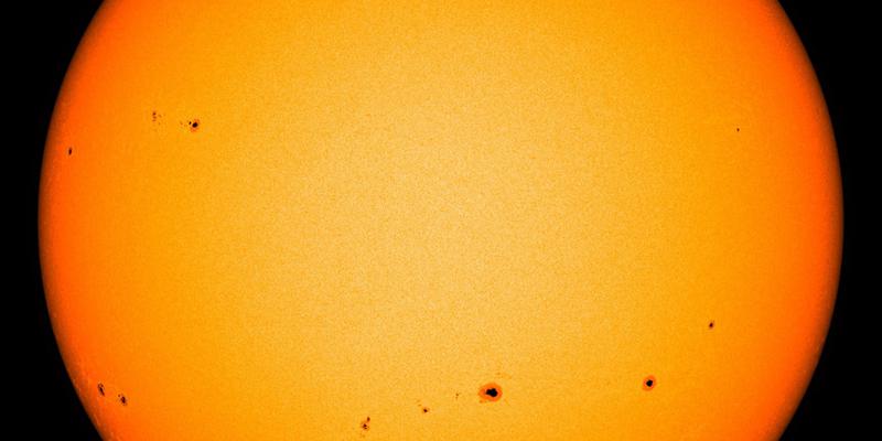 Image showing groups of sunspots as dark patches which lie in bands above and below the Sun's equator