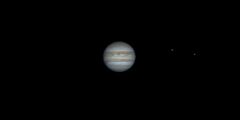 Il pianeta Giove con due delle quattro lune galileiane (visibili come punti luminosi) che gli orbitano attorno.