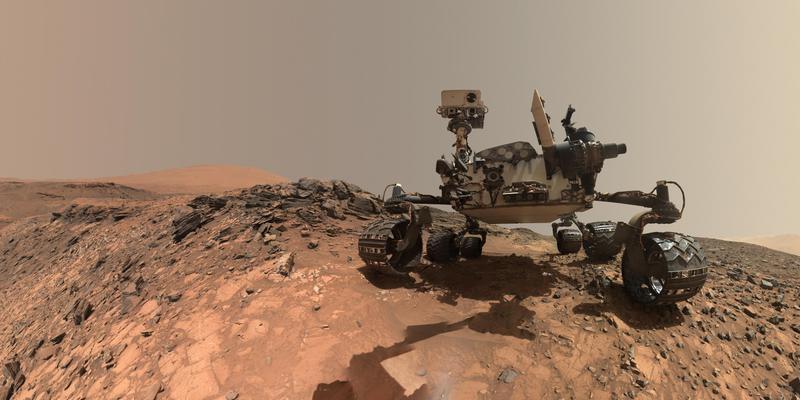 The NASA Mars rover Curiosity stands on a hill on Mars.