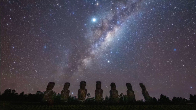 The Milky Way rises over seven silently vigilant stone statues