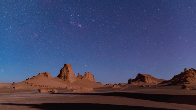 The bow tie shaped Orion over dry, rocky outcrops. Sirius appears as a bright star between two pillars of rock