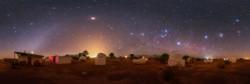 Un gruppo di osservatori di fronte a un cielo buio. Un arco di luce curva dal basso a sinistra. Sono visibili diverse stelle.