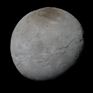 Pluto’s moon Charon is roughly spherical with craters and the reddish north polar region known as Mordor Macula.