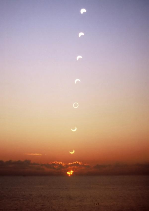 Otto immagini del Sole che sorge. A partire dal basso la Luna si muove sul Sole dall'alto a sinistra verso il basso a destra.