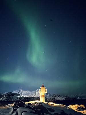 Un fascio di luce verde si alza su un faro illuminato