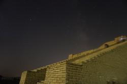 Un cielo stellato, compreso il bagliore diffuso della Via Lattea dietro una piramide di mattoni di fango a gradoni.