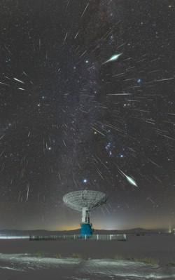 تنبعث الخطوط الساطعة التي أنشأتها الشهب من نقطة في السماء فوق طبق التلسكوب الراديوي.