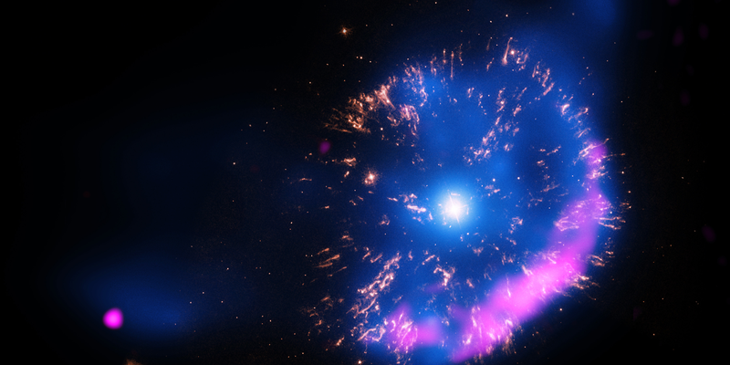 A point-like source surrounded by a blue glow, yellow radial streaks and a pink shell.