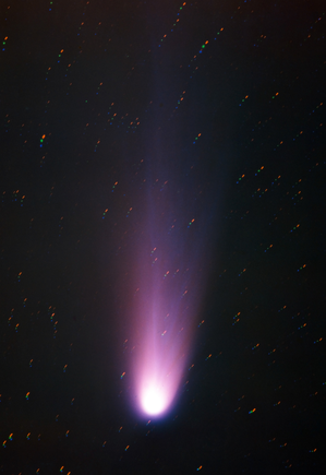 Halley's Comet with a bright tail of gas and dust pointing to the upper right. The stars in the image are elongated.