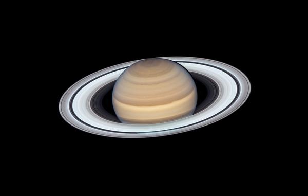 Il pianeta Saturno con strisce di nubi brunastre e i suoi sottili ed estesi anelli grigiastri