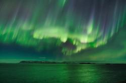 Wavy horizontal green bands, punctuated by dark vertical stripes. almost appear to rain down on a watery landscape