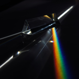 A prism refracting a beam of white light into a spread of rainbow colors from (right to left) blue to green to yellow to red