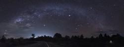 La curva della Via Lattea su strada. In basso a sinistra, due stelle luminose creano una linea verso  una forma di aquilone
