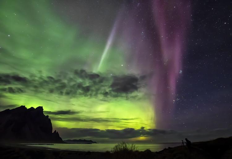 The left side of the image shows the sky glowing green. The right side has a darker sky but has green streaks