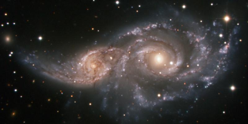 Two spiral galaxies embracing in their early stages of merger with distortions on the smaller galaxy visible