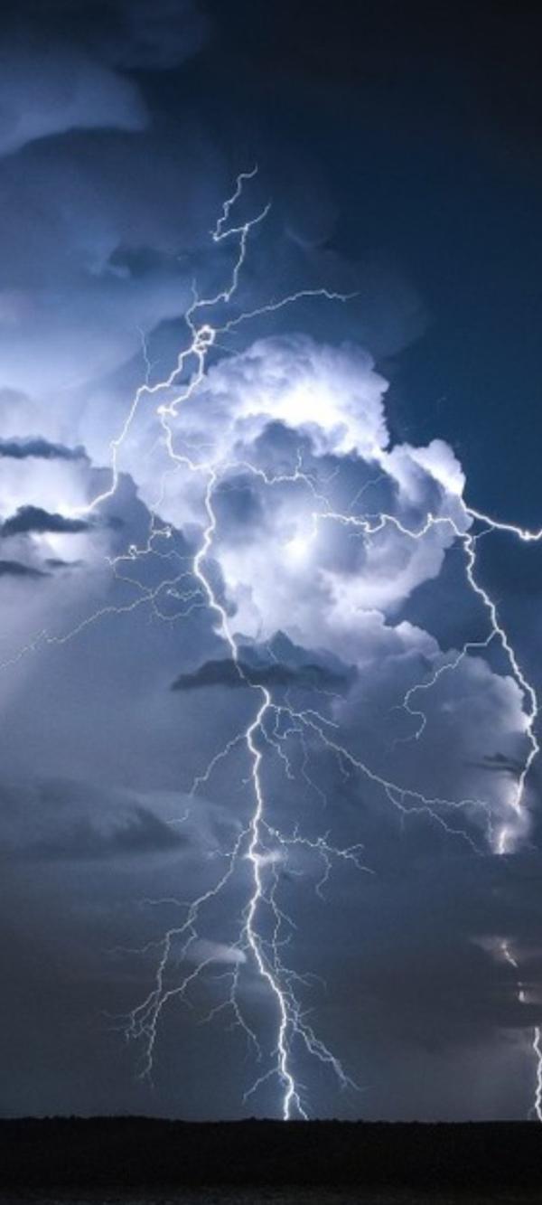 Lightning forks and appears to hit the ground in front of a cloudy sky