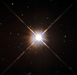 Proxima Centauri appears as a bright point with diffraction spikes. Several fainter stars are in the background.