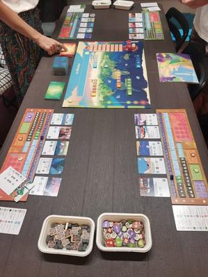 Teachers standing over a table with the board, cards and tokens for a board game