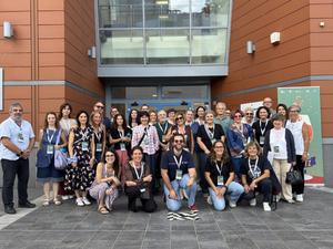 Participants posing for a photo outside the entrance to a building