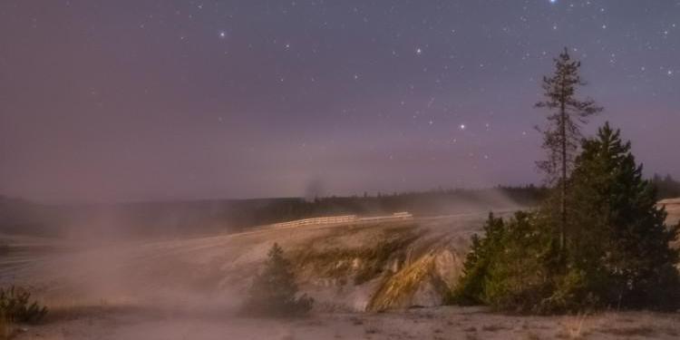 Uno specchio d'acqua fumante sotto il cielo notturno, in cui risalta un gruppo di 7 stelle a forma di padella col manico.