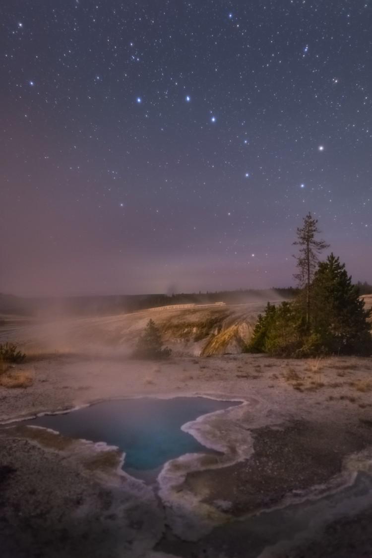 Uno specchio d'acqua fumante sotto il cielo notturno, in cui risalta un gruppo di 7 stelle a forma di padella col manico.