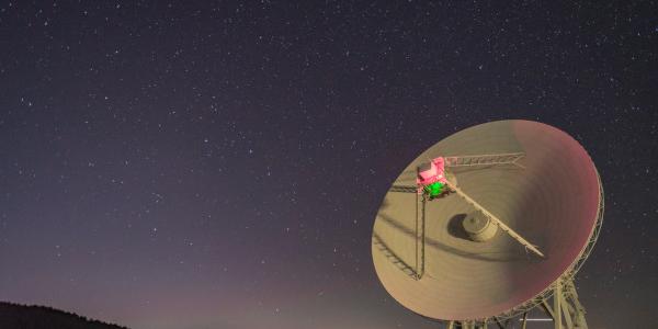 La parabola di un radiotelescopio ruota mentre l'Orsa Maggiore si muove nel cielo retrostante.