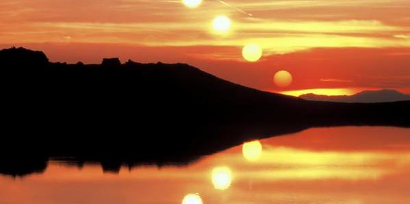 The Sun sinks from the top left of the image towards the middle. This path is reflected in the surface of the lake.