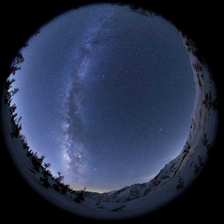 Una foto a tutto cielo della Via Lattea come un fiume diffuso di luce, interrotto da una banda centrale di macchie scure.