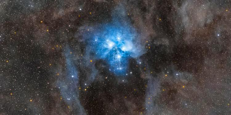 A cluster of brilliant blue stars illuminate the surrounding nebular gas.