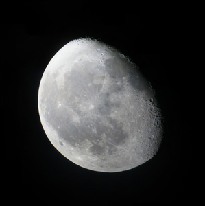 The Moon is mostly illuminated but a thin crescent on the right side of the Moon is in darkness