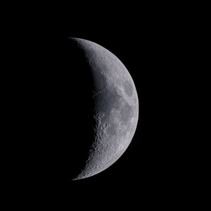 The moon is mostly dark but a thin crescent on the right is illuminated.
