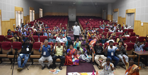Many workshop participants in a lecture theatre holding models made of colourful paper