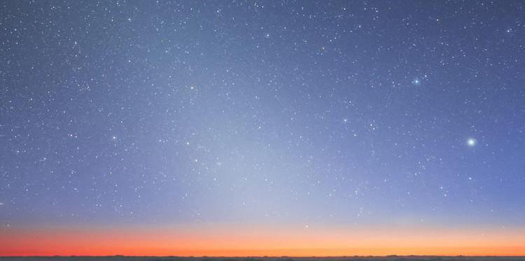 Un bagliore omogeneo e diffuso si estende dall'orizzonte verso l'alto a sinistra. In alto a sinistra due stelle luminose.